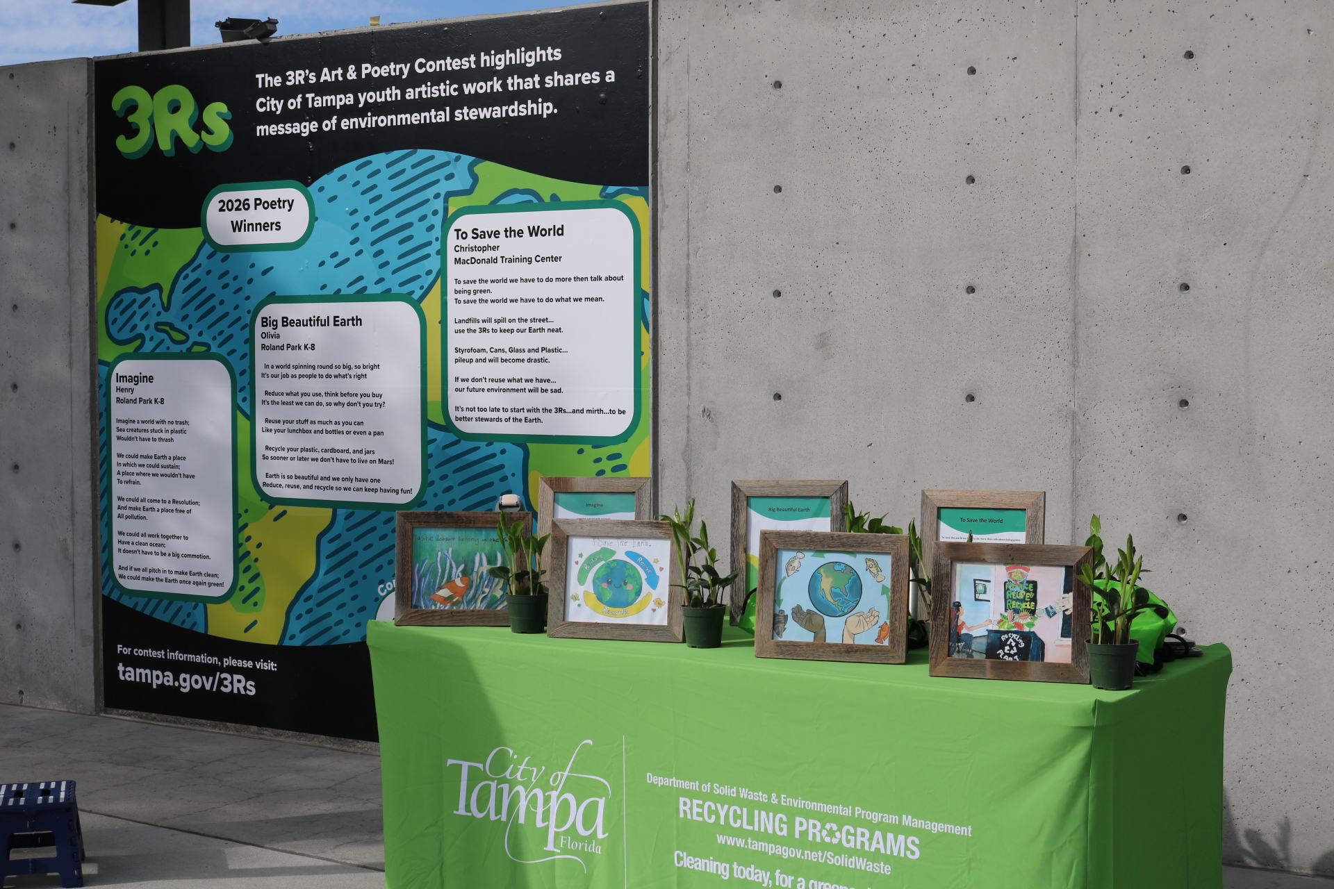 large sign with three poetry bubbles and a green table with picture frames holding artwork.